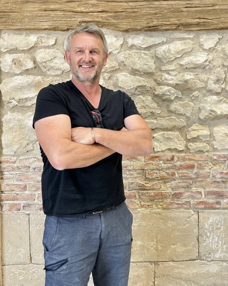 Portrait de Thierry BKLK devant un décor de pierre et de brique lors de son perfectionnement professionnel en Espagne