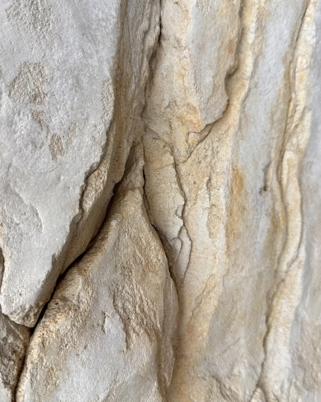 Roche sculptée claire, fissures verticales et patines crème et ocre.