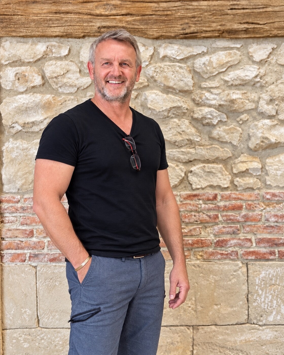 Thierry BKLK — fondateur et artisan créateur Authenti-Stones™ Thierry BKLK, fondateur d’Authenti-Stones™, devant un décor mural en pierre et brique